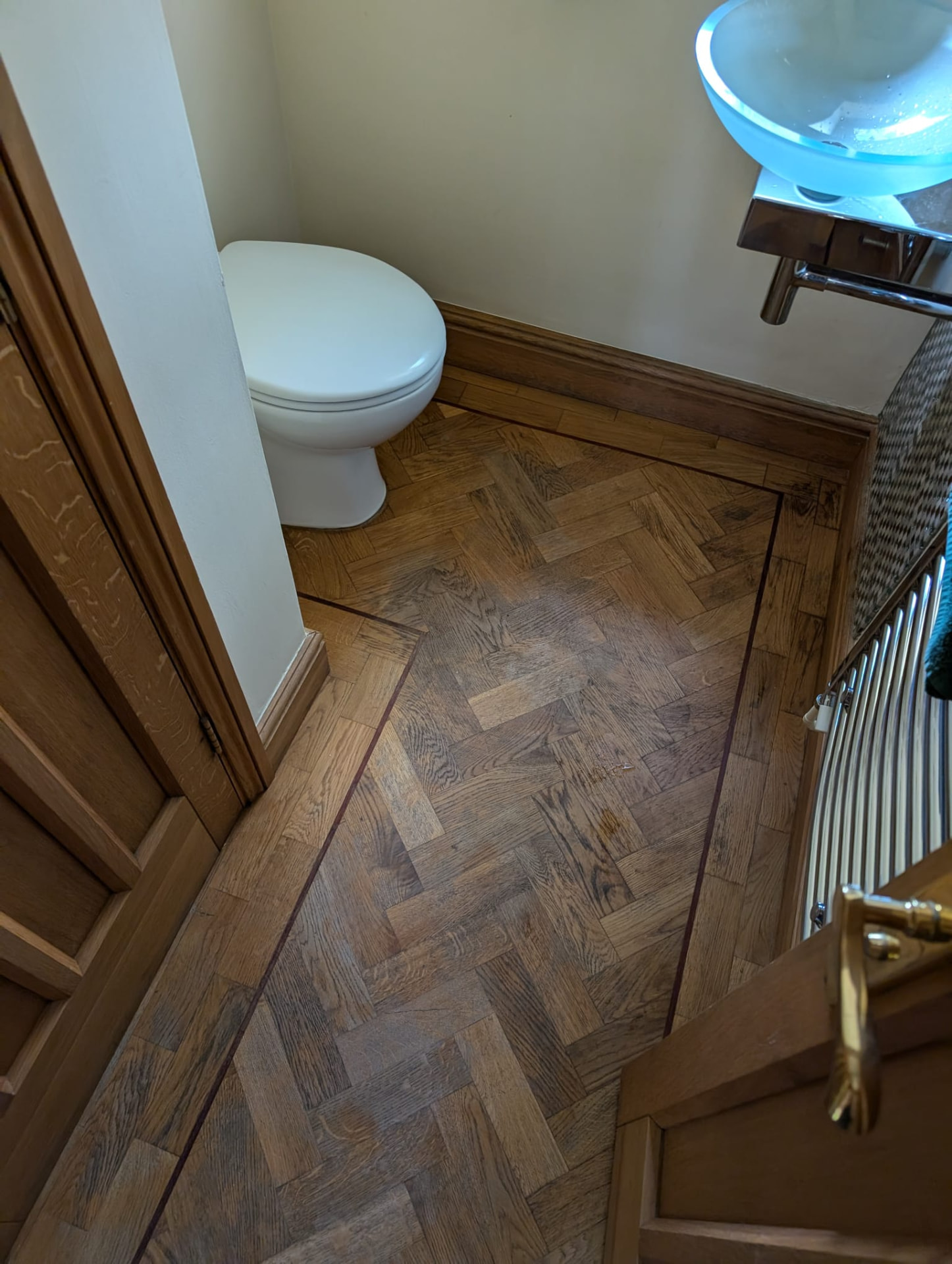 Dark, worn oak parquet floor in a cloakroom before sanding
